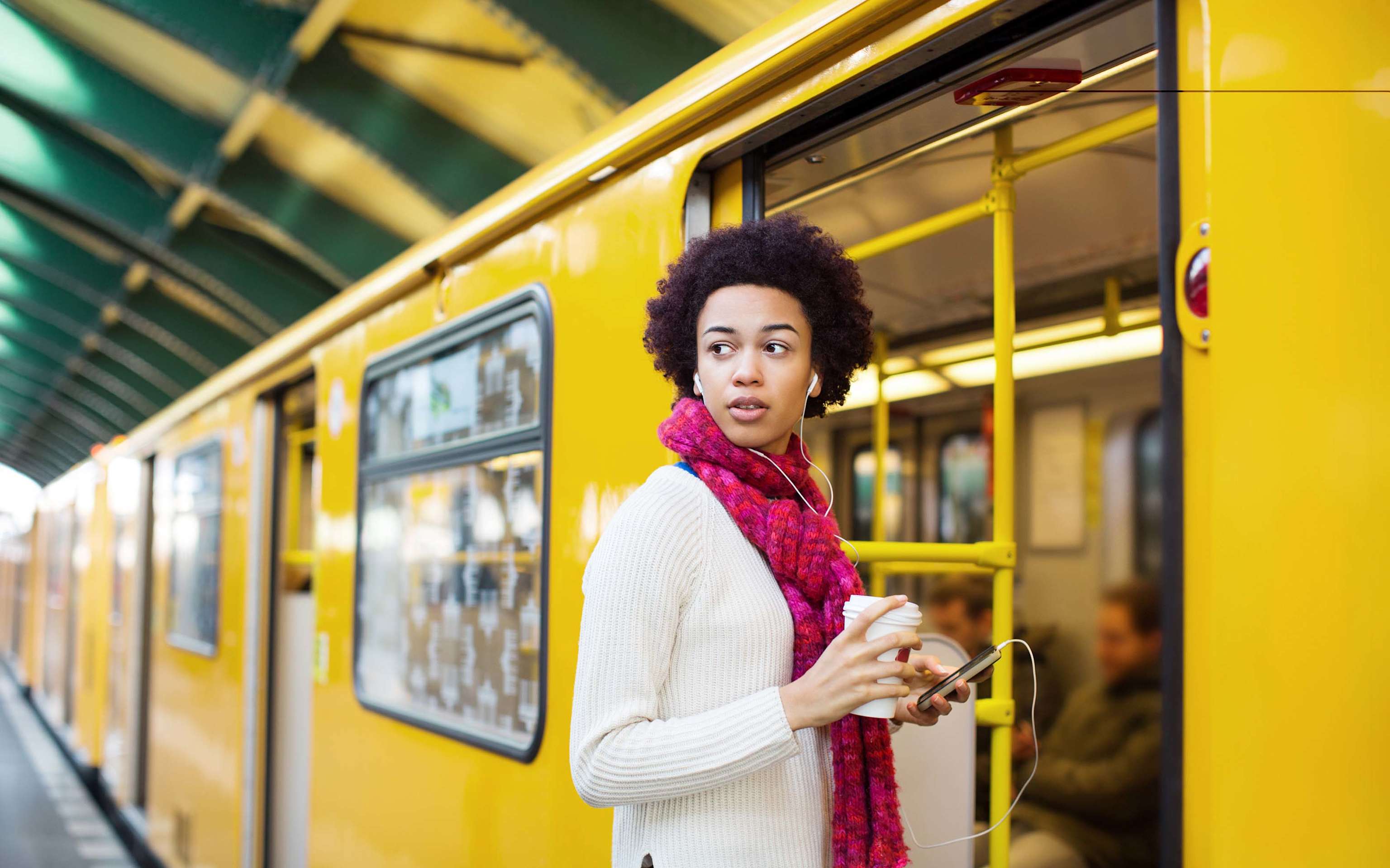 Frau mit Smartphone und Kopfhörern steigt in Berliner Straßenbahn Frau mit Smartphone und Kopfhörern steigt in Berliner Straßenbahn