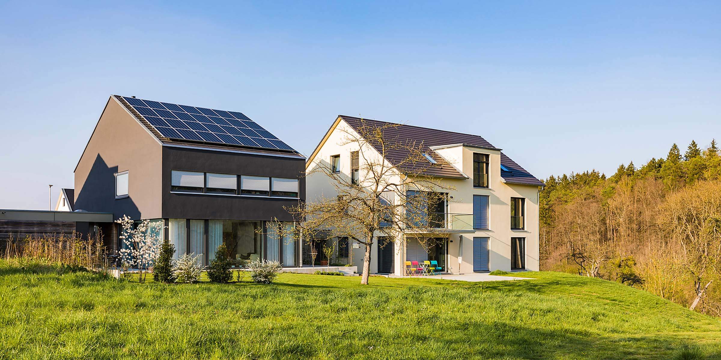 Solarstrom lokal mit Nachbarn teilen – neu über Energy Sharing Modernes Einfamilienhaus mit Photovoltaik-Anlage steht neben Haus ohne Photovoltaik-Anlage