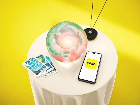 Behalt deine Stromkosten im Blick - Mit der Yello App geht's einfach Eine Glaskugel liegt auf dem Tisch und ein Handy mit Yello Logo daneben - KI generiert