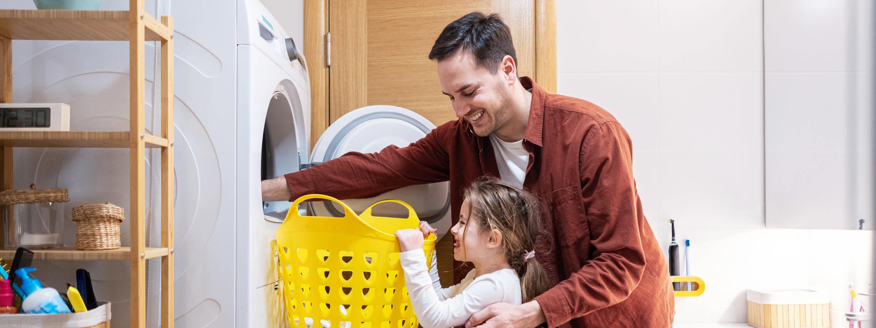 Vater und Tochter holen die Wäsche aus dem Trockner Vater und Tochter holen die Wäsche aus dem Trockner