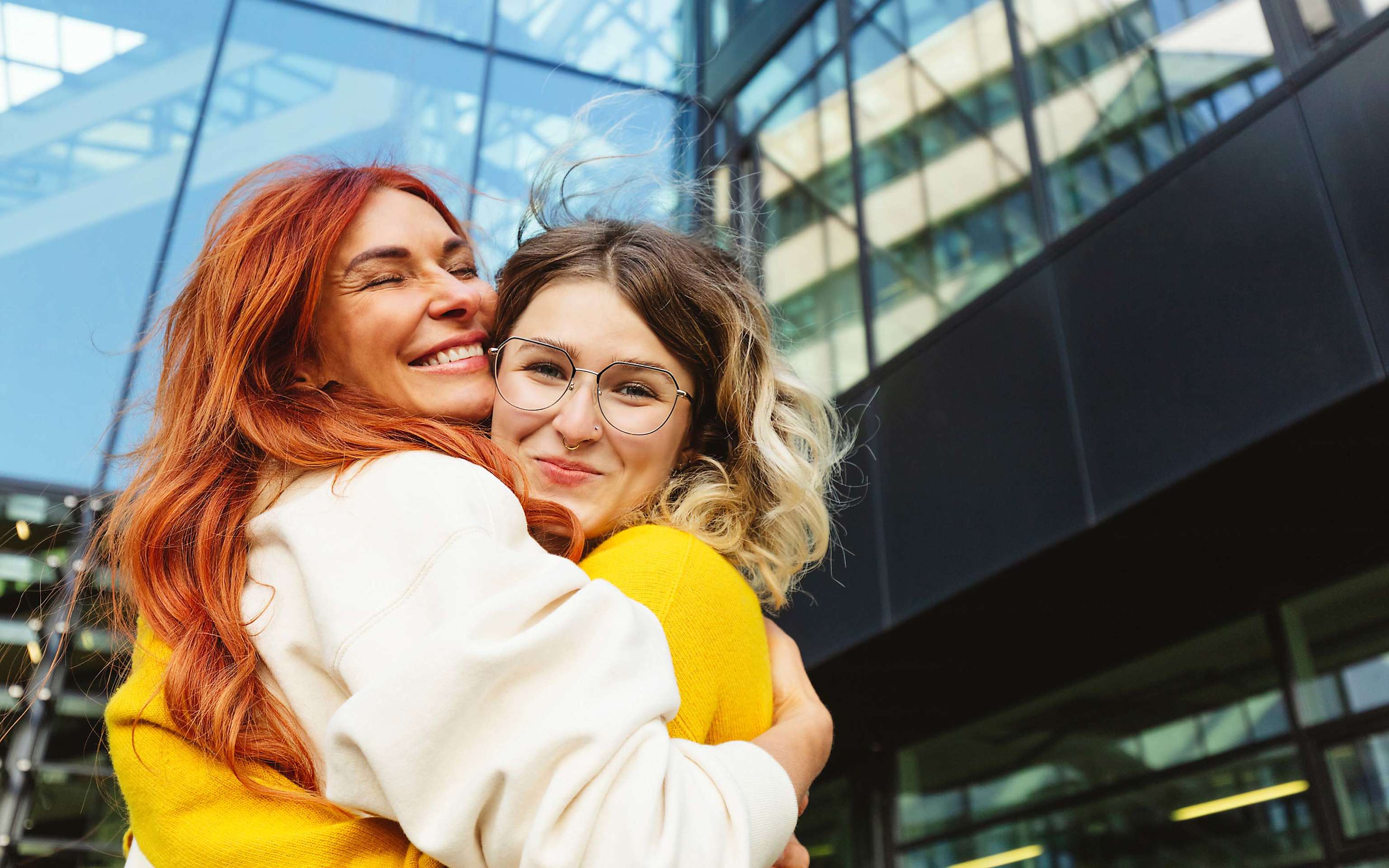 Zwei glückliche Frauen, die sich vor einem Gebäude umarmen Zwei glückliche Frauen, die sich vor einem Gebäude umarmen