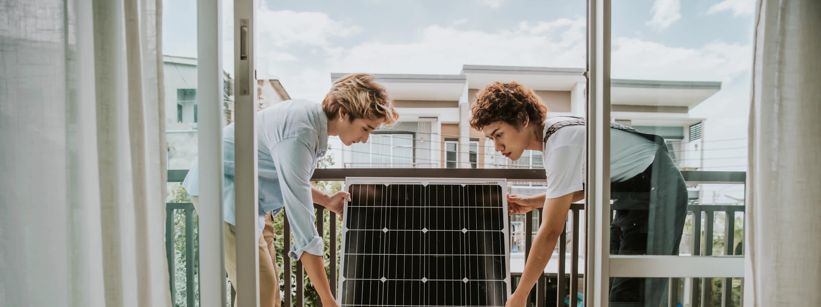 Zwei junge Frauen installieren ein Solarmodul auf dem Balkon Zwei junge Frauen installieren ein Solarmodul auf dem Balkon