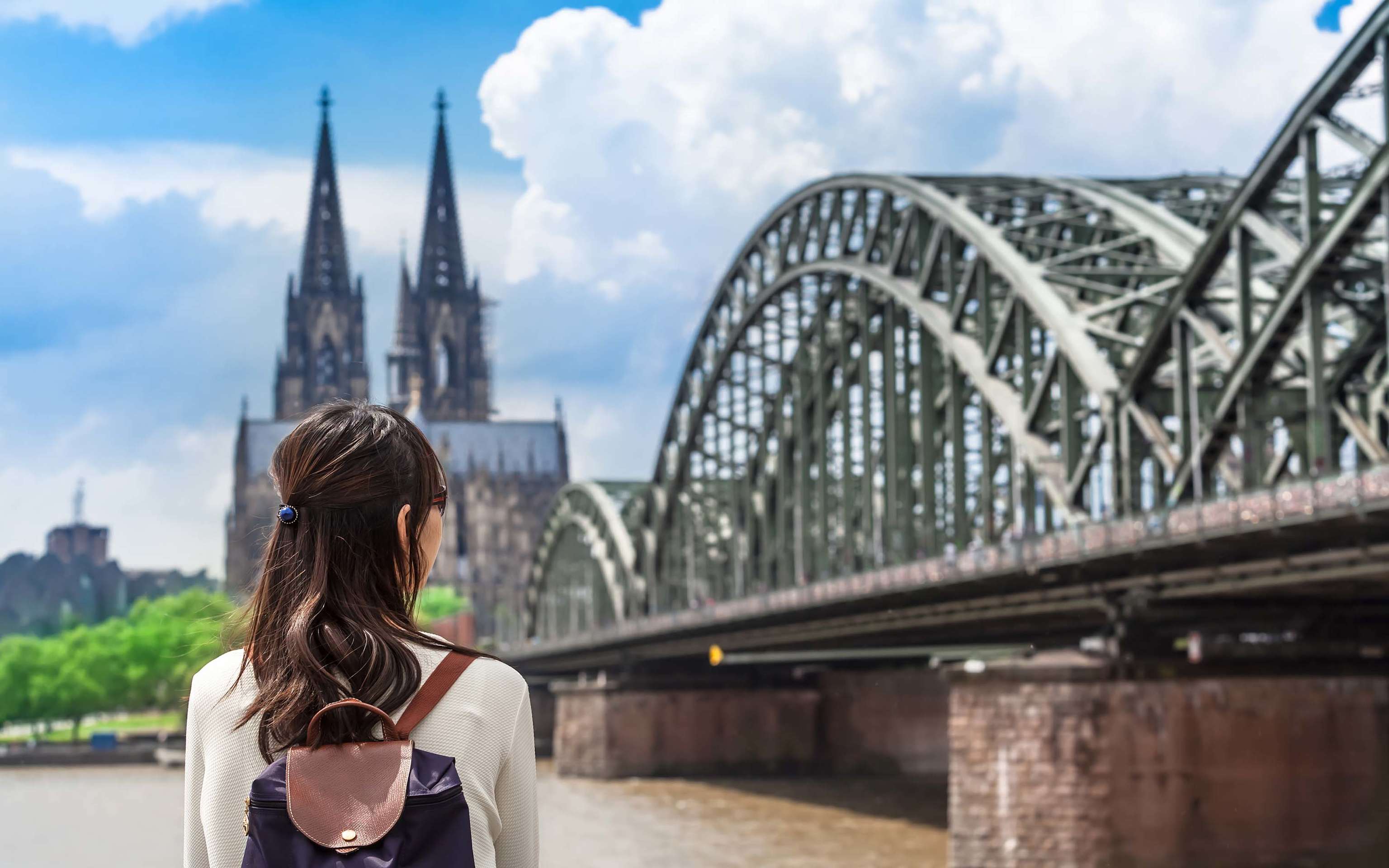 Eine Frau am Rhein schaut auf die Hohenzollernbrücke mit Kölner Dom Eine Frau am Rhein schaut auf die Hohenzollernbrücke mit Kölner Dom