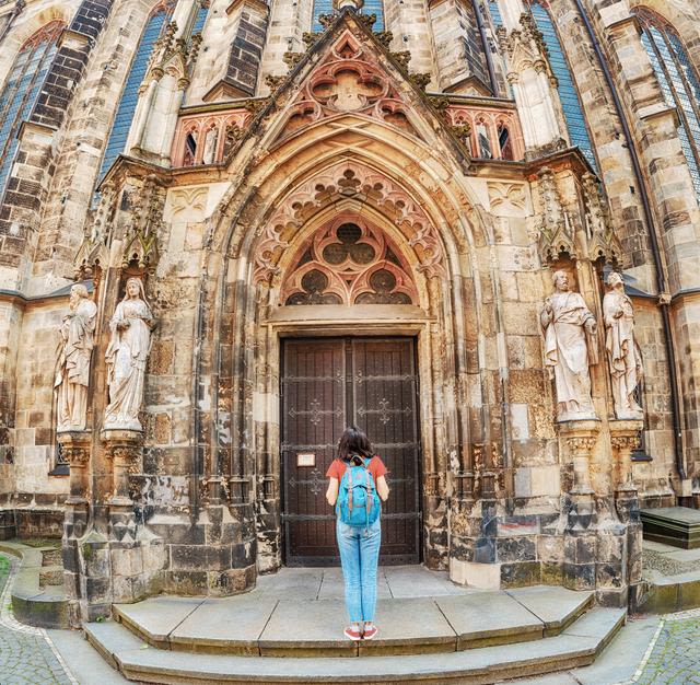 Stromanbieter für Leipzig. Gesucht? Gefunden. Frau mit Rucksack steht am Eingang der Leipziger Thomaskirche.