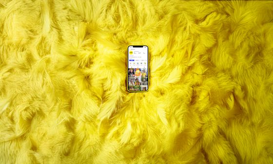 Yello Handy Federn Instagram Ein Smartphone mit geöffnetem Yello Instagram Account liegt auf gelben Federn