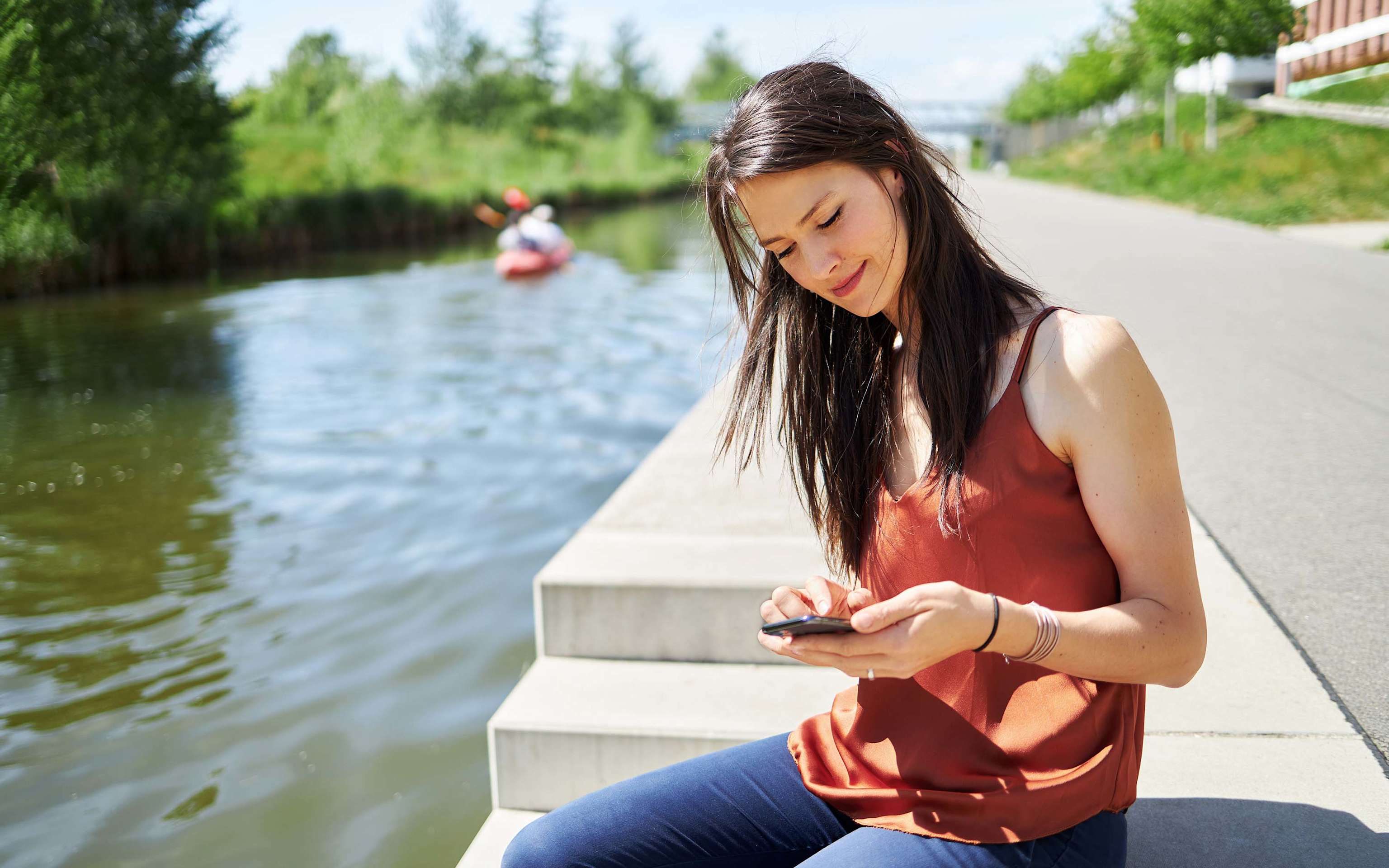 Junge Frau chillt mit einem Handy in der Hand in Leipzig nah am Wasser Junge Frau chillt mit einem Handy in der Hand in Leipzig nah am Wasser