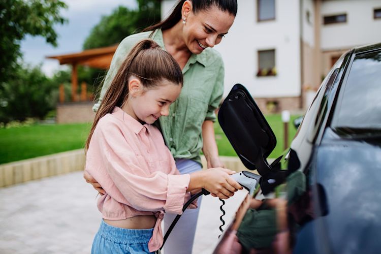 Ein E-Auto zu laden ist kinderleicht und mit Wallbox schnell Frau mit kleinem Mädchen laden zusammen ein E-Auto.