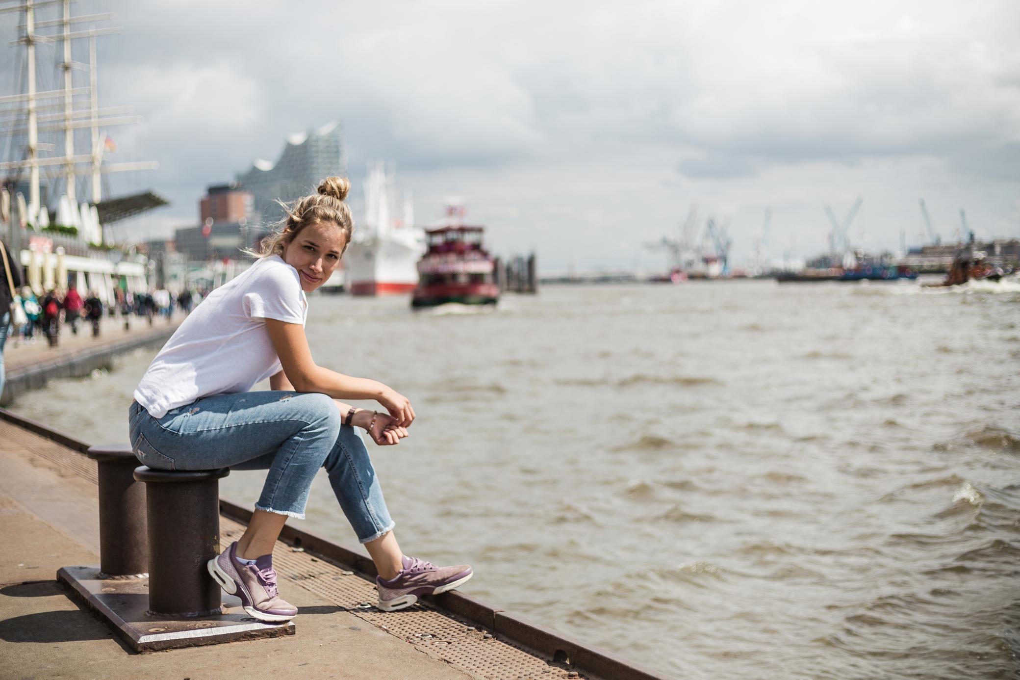 Frau sitzt am Hamburger Hafen.