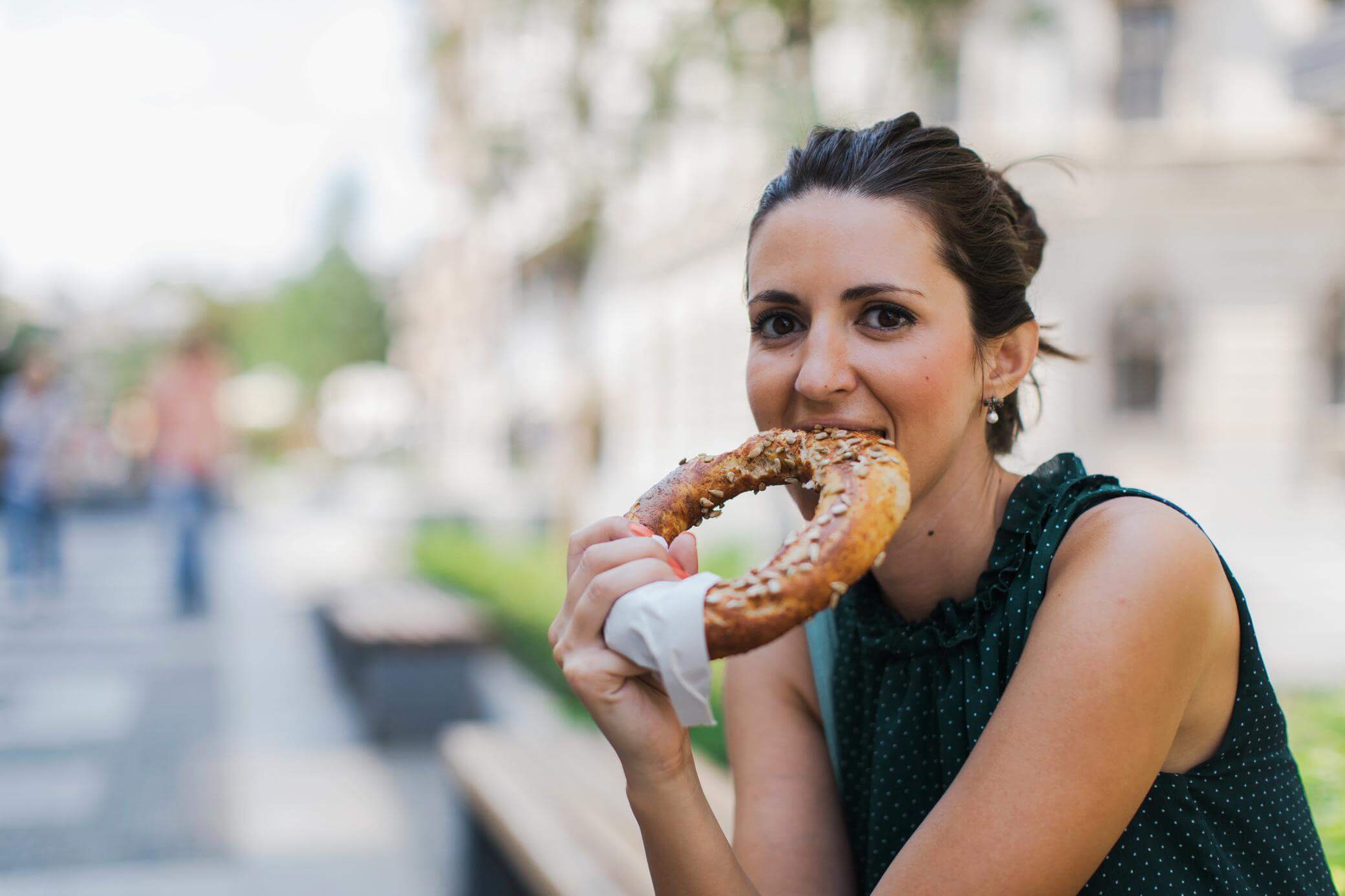 Eine Frau isst eine Brezel in der Stadt
