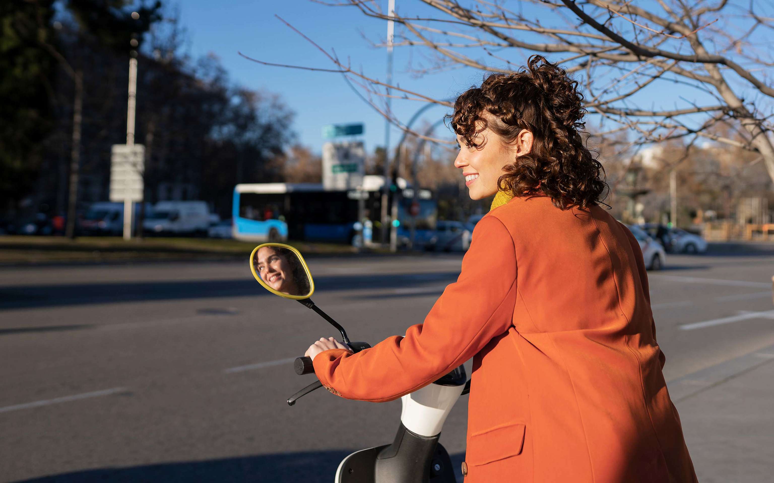 Lächelnde Frau fährt mit dem Elektro-Roller durch die Stadt Lächelnde Frau fährt mit dem Elektro-Roller durch die Stadt