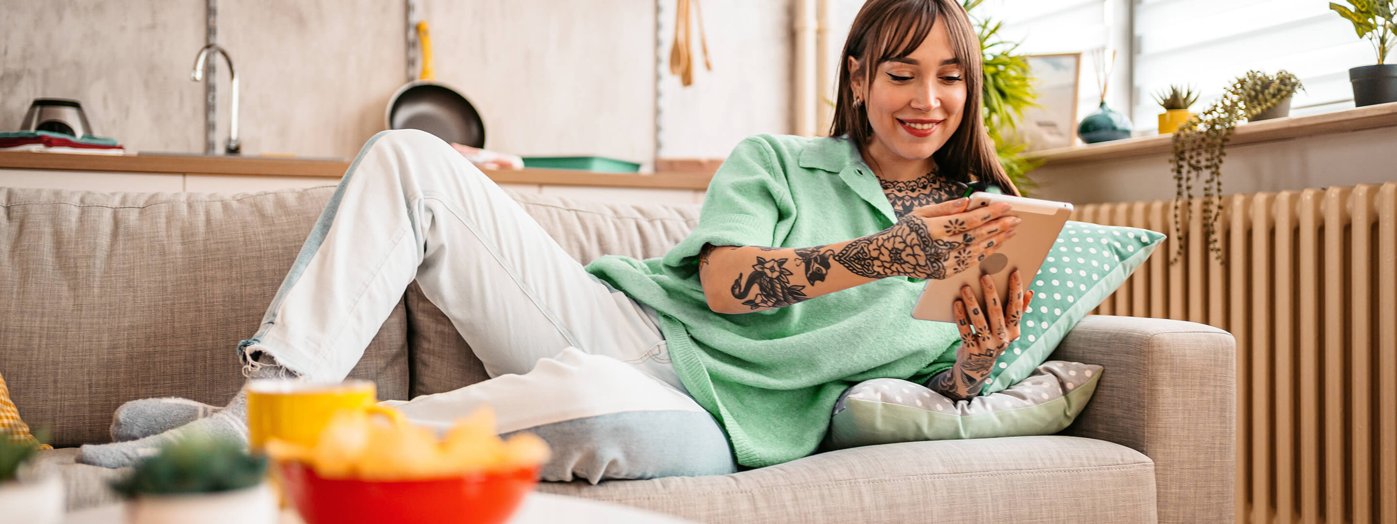 Mach dir dein Zuhause smart mit sinnvollen digitalen Helfern Junge Frau auf dem Sofa steuert mit dem Tablet ihre Smart-Home-Geräte