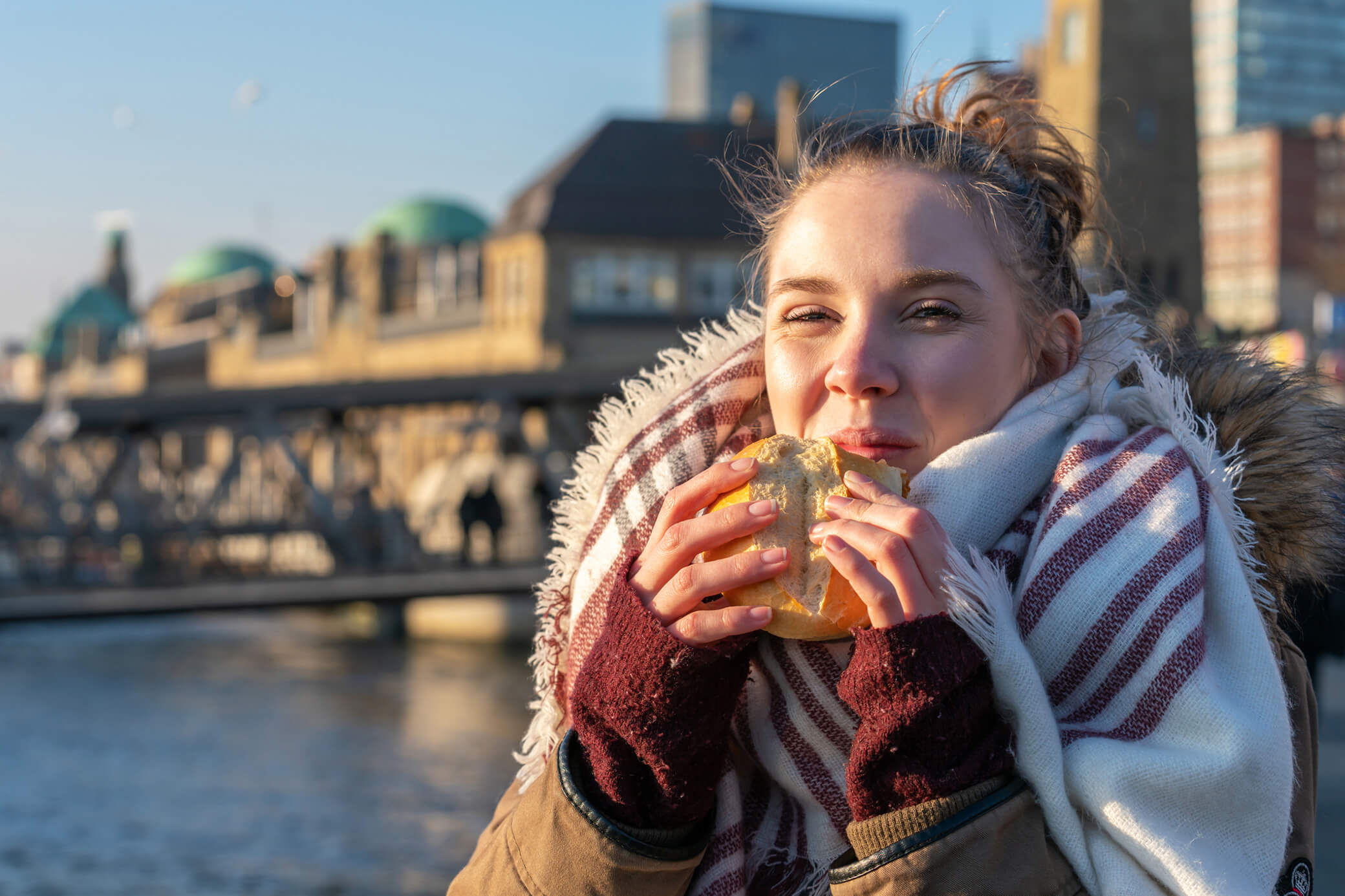 Eine Frau geniesst ein Fischbrötchen im Hamburger Hafen