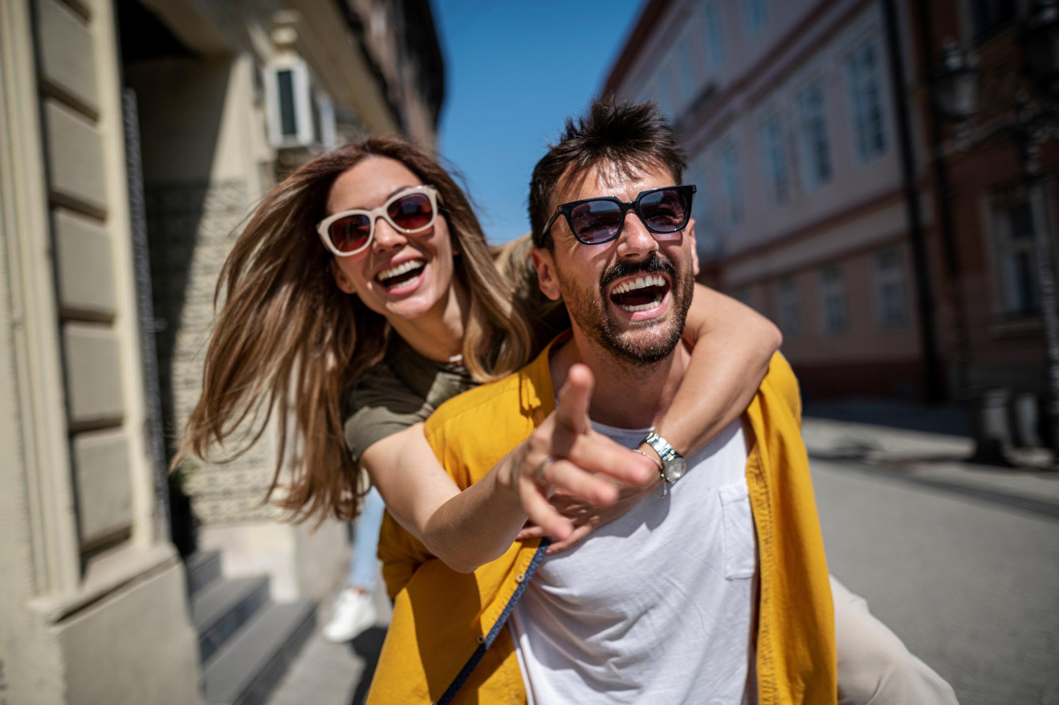 Entdecke Düsseldorf ganz neu und grün mit Yello - wir begleiten dich mit Spaß! Paar entdeckt Düsseldorf mit Freude. Ein Mann trägt eine Frau huckepack. Spaß in der Innenstadt.