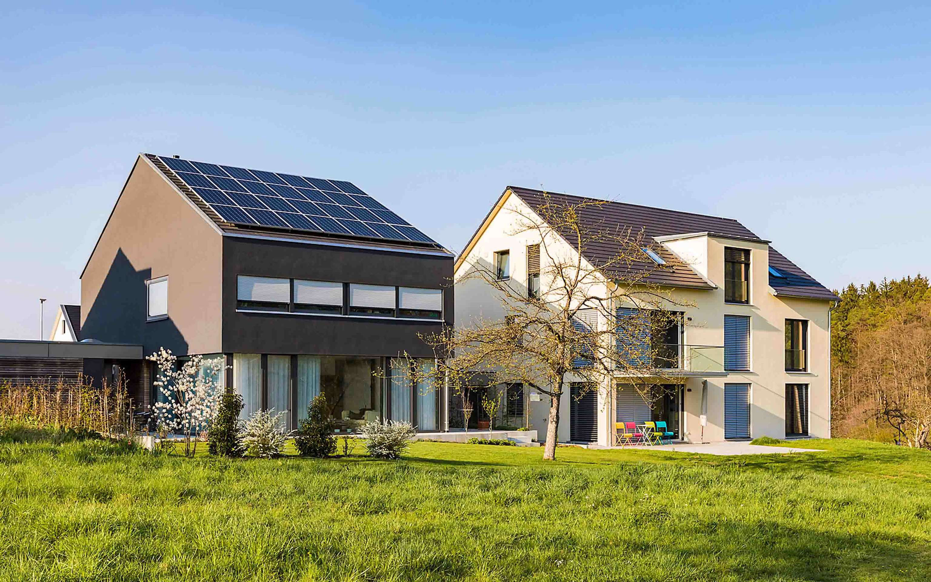 Modernes Einfamilienhaus mit Photovoltaik-Anlage steht neben Haus ohne Photovoltaik-Anlage Modernes Einfamilienhaus mit Photovoltaik-Anlage steht neben Haus ohne Photovoltaik-Anlage