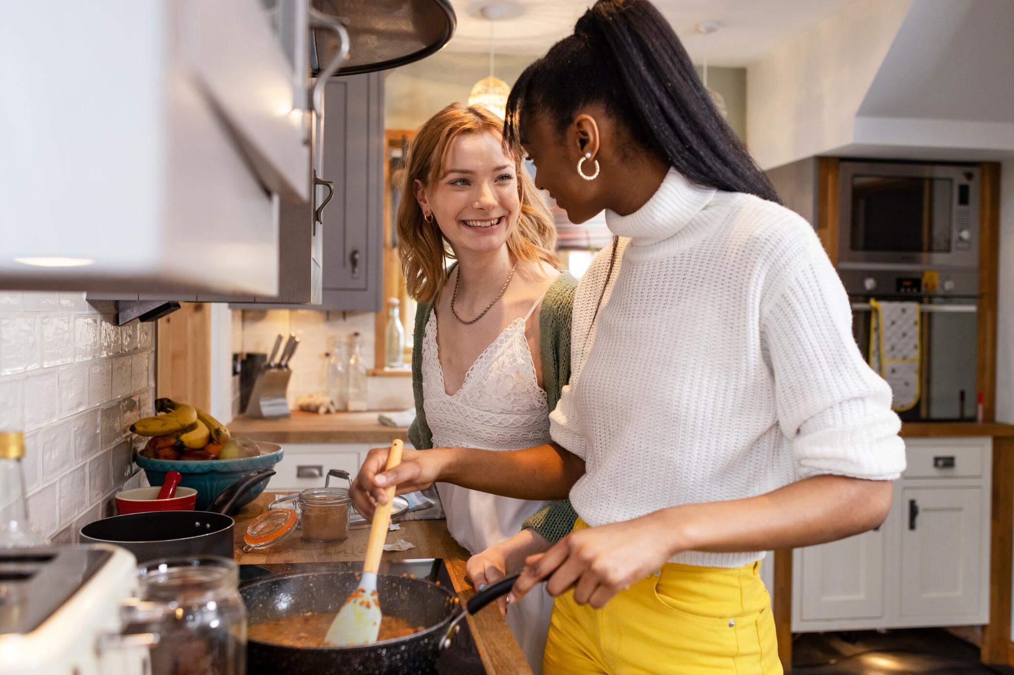 Zwei Freundinnen kochen eine Mahlzeit in der Küche